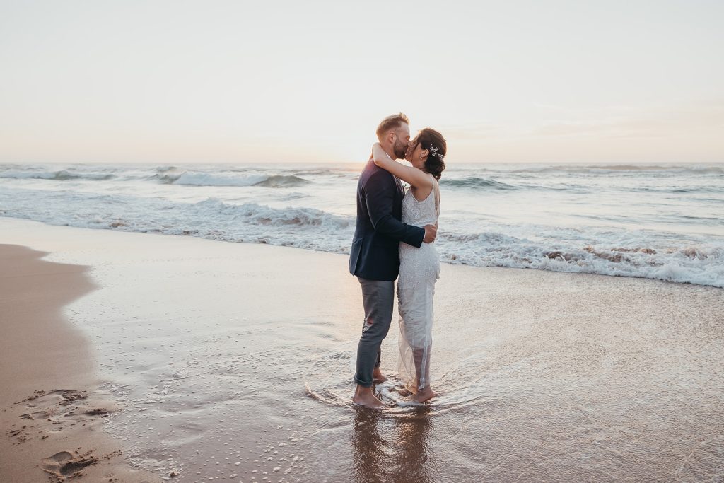 A couple kissing pose for beach wedding in portugal