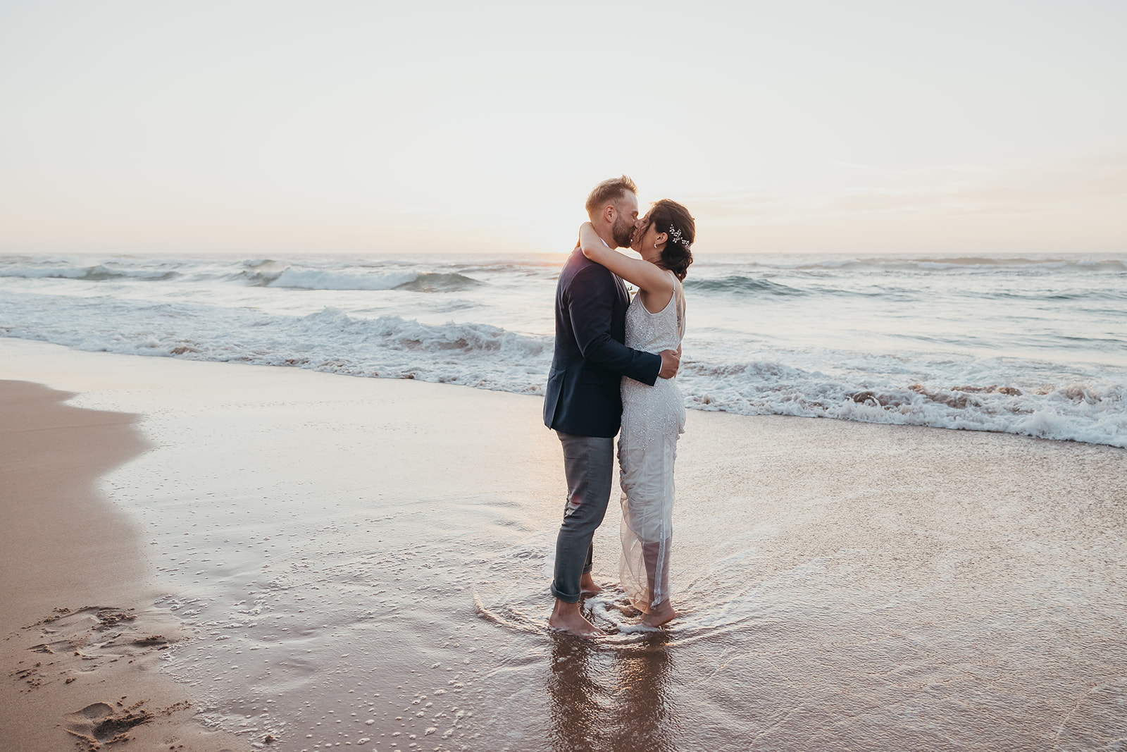 A couple kissing pose for beach wedding in portugal