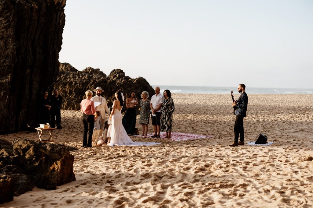 A beach wedding ceremony with guests in the background